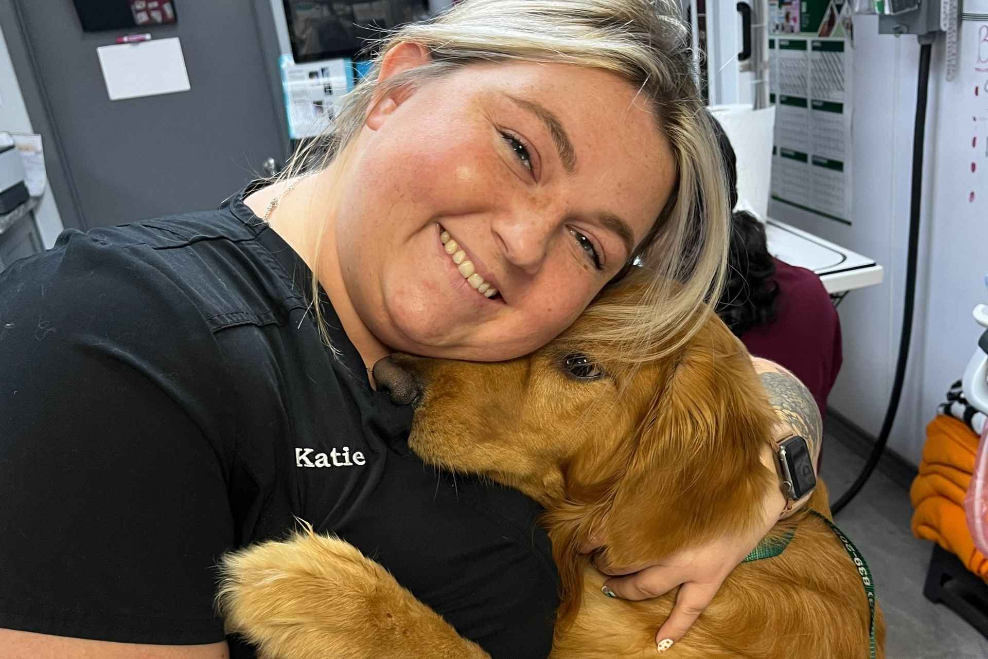 A doctor is hugging a golden retriever in a veterinary office
