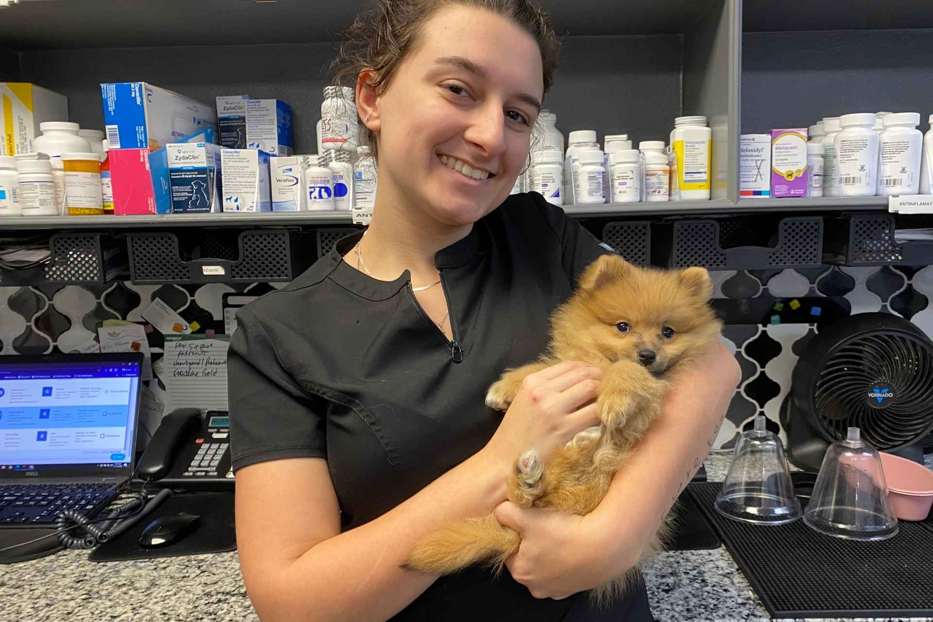 A person holding a small dog in a pharmacy